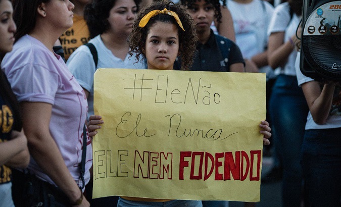 Brazilian girl holds a sign with the anti-Bolsonaro hashtag #EleÑao.