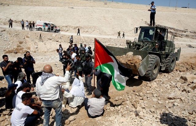 Palestinians protest in front of an Israeli bulldozer against Israel's plan to demolish the Palestinian Bedouin village of Khan al-Ahmar, Sept. 14, 2018.