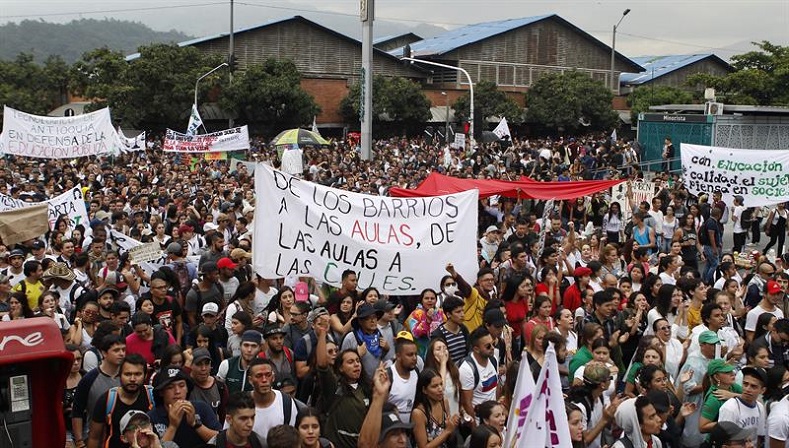 A protester in Medellin holds a sign which reads: 