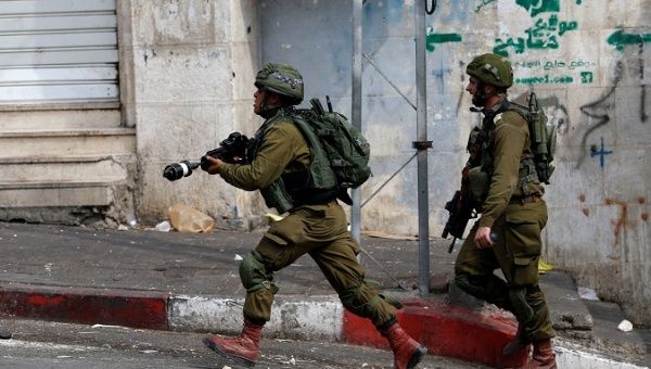 Israeli soldier runs during clashes with Palestinians in Hebron, in the occupied West Bank