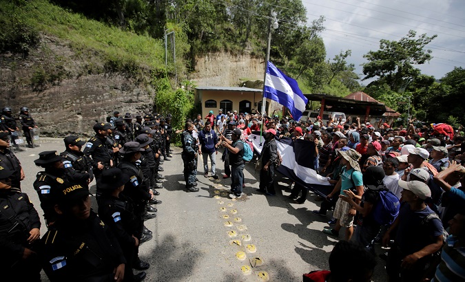 Guatemala's police officers stand as Honduran migrants, part of a caravan trying to reach the U.S., arrive at the border between Honduras and Guatemala.
