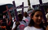 Relatives of women who were either murdered or disappeared hold crosses with names of ther relatives as they take part in a march for the Elimination of Violence Against Women in Mexico.