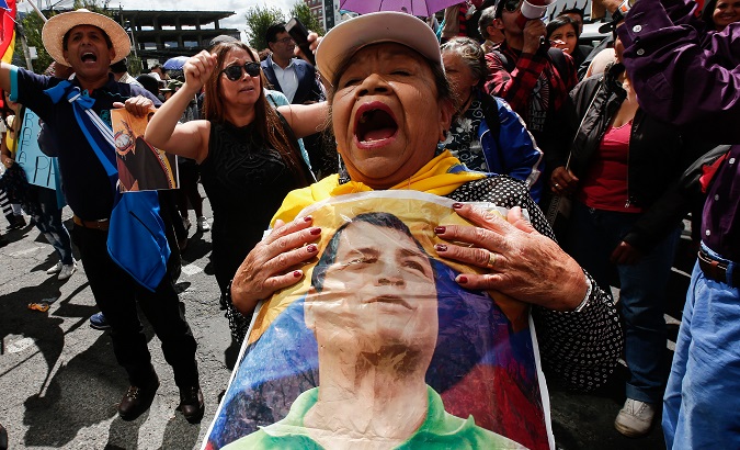 Una mujer sostiene una foto del el expresidente Rafael Correa durante un acto politico en Quito, Ecuador, 18 de junio de 2018.