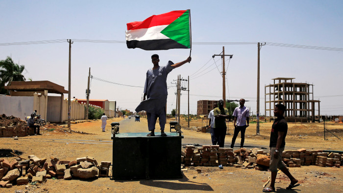 Un manifestante sudanés sostiene una bandera nacional en una calle bloqueada de Jartum.