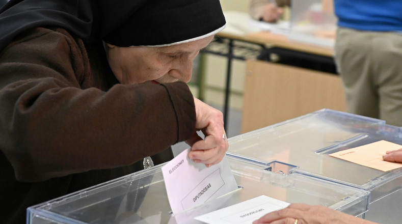 Una religiosa deposita su voto en la urna de un colegio electoral en Alcalá de Henares.
