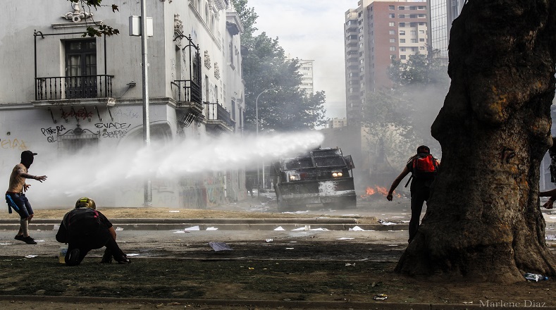Encapuchados sin temor frente a al carro lanza agua (Santiago de Chile, 20 de Octubre 2019).