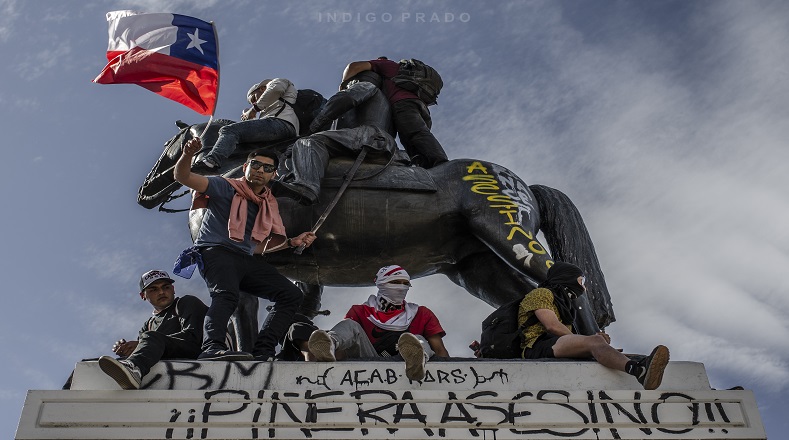 Manifestantes arriba de estatua del general Baquedano en plaza céntrica de la capital (Santiago de Chile).