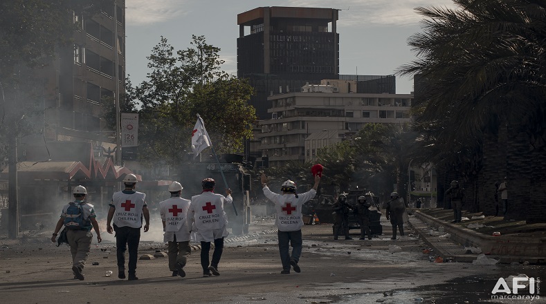 Voluntarios de la Cruz Roja se dirigen con las manos en alto hacia carabineros para intentar frenar la represión desmedida (Santiago de Chile, 22 de octubre de 2019).