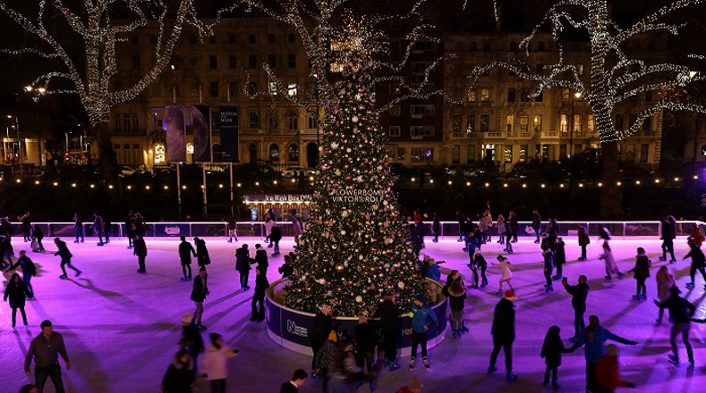Diversas personas patinan en la pista de hielo en el Museo Nacional de Historia de Londres, Reino Unido, alrededor de un enorme árbol de Navidad.