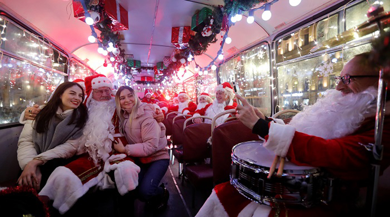Un músico disfrazado de Papá Noel comparte con pasajeros en un autobús decorado para las celebraciones de Navidad y Año Nuevo en Rusia