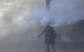 Una mujer es rociada con un cañón de agua durante una protesta contra el gobierno de Chile en Santiago.