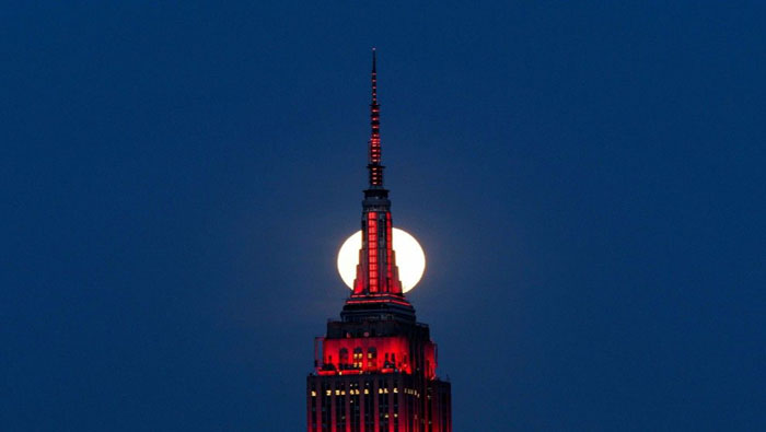 Detrás del Empire State Building, en Nueva York, Estados Unidos, la "Superluna rosa" que no es rosa, sino en fotografías editadas, resplandeció con el 15 por ciento extra de luz que la caracterizó.