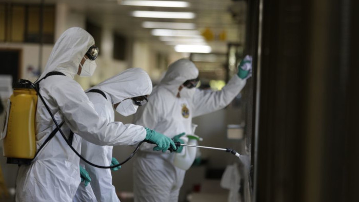Integrantes de la Marina portan trajes protectores mientras rocían desinfectante en el Hospital Regional de Asa Norte, en Brasilia.