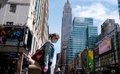 Una mujer con mascarilla camina por una calle de Nueva York, donde están cerrados los negocios no esenciales.
