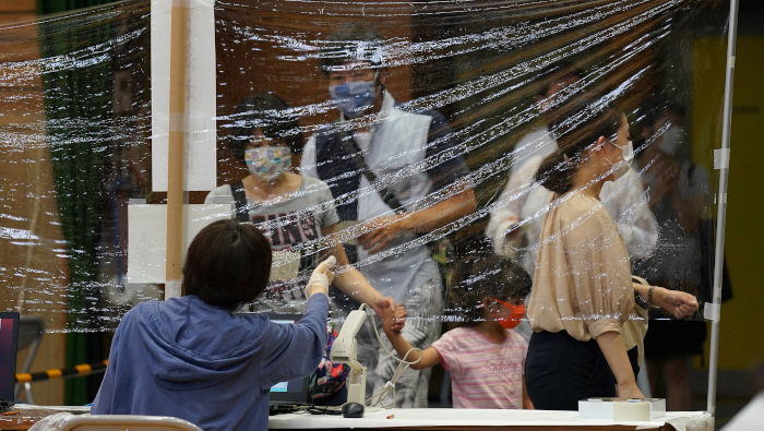 Los votantes usan cubrebocas mientras se preparan para emitir su voto en la elección de gobernador de Tokio.