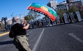 A protester waves a Mapuche flag in front of a Carabineros Special Forces contingent during a protest this Friday in Santiago