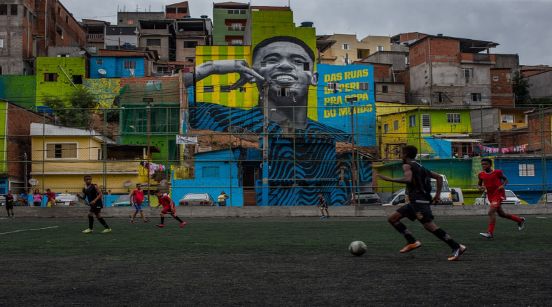 Frente a un mural que recrea la imagen del conocido astro brasileño Gabriel Jesus, un grupo de jóvenes juega fútbol en una cancha del barrio de Jardim Peri de Sao Paulo, donde creció el jugador del Manchester City.   