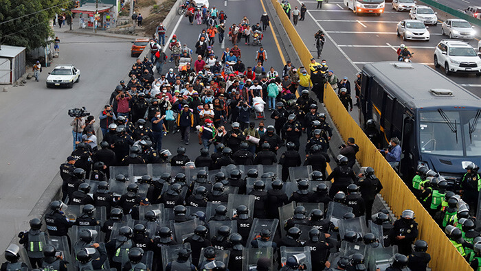Migrantes son frenados por las fuerzas de seguridad al llegar a la capital mexicana.