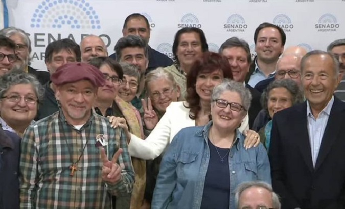 Dressed in a white jacket, Cristina Fernandez-Kirchner poses with Catholic activists, Sept. 15, 2022.