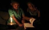 Children read by candlelight, South Africa, 2022.