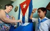 A Cuban citizen enters her ballot into a voting booth. 