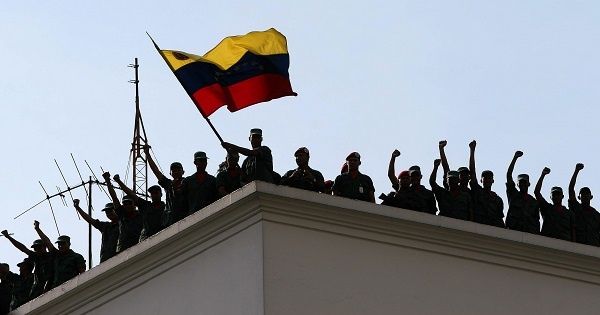Venezuelan soldiers loyal to Hugo Chavez wave the country's flag atop their barracks after retaking the presidential palace from the de facto regime, April 13, 2002.