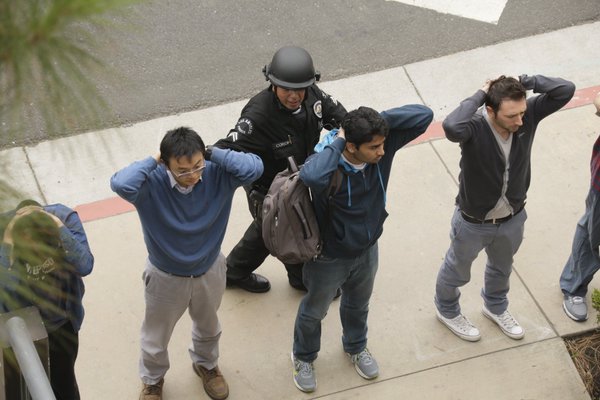 Un agente de la policía revisa a estudiantes de la universidad californiana, tras el ataque armado.