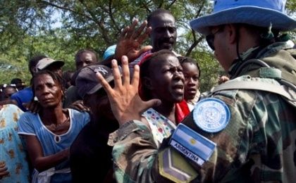 A soldier with the U.N. Stabilization Mission in Haiti gestures to local residents waiting to receive bottled water.