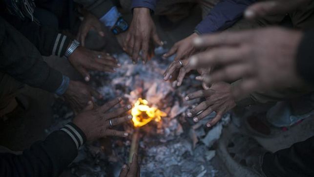 Un grupo de jóvenes se calienta las manos junto al fuego en un mercado en Katmandú, Nepal.