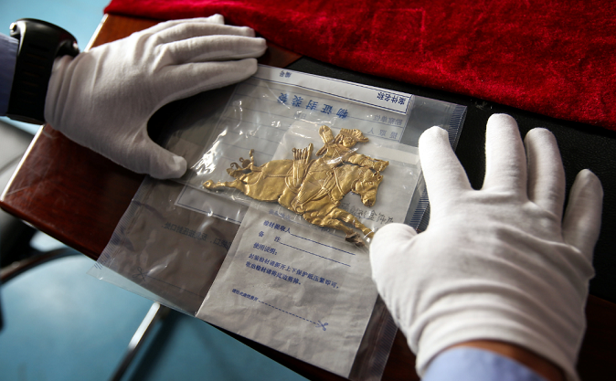 A police officer displays a retrieved cultural relic which was stolen from an ancient burial site, at a police station in Dulan county, Qinghai province, China August 2, 2018. China Daily via REUTERS