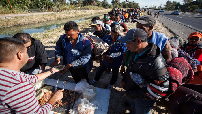 Un hombre ofreció comida a personas de la caravana migrante mientras continuaban su trayecto el martes por la ciudad de Mexicali rumbo a la fronteriza Tijuana.