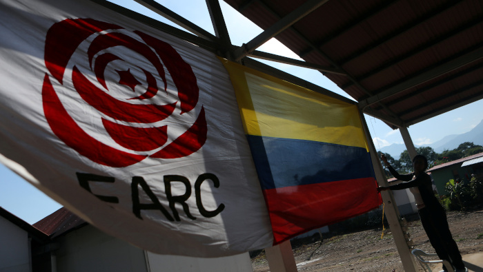 Una mujer cuelga una bandera colombiana junto a la bandera del partido político de la Fuerza Alternativa Común Revolucionaria (FARC).