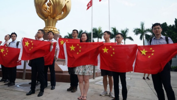 Jóvenes sostienen banderas nacionales de China durante un acto en Hong Kong.