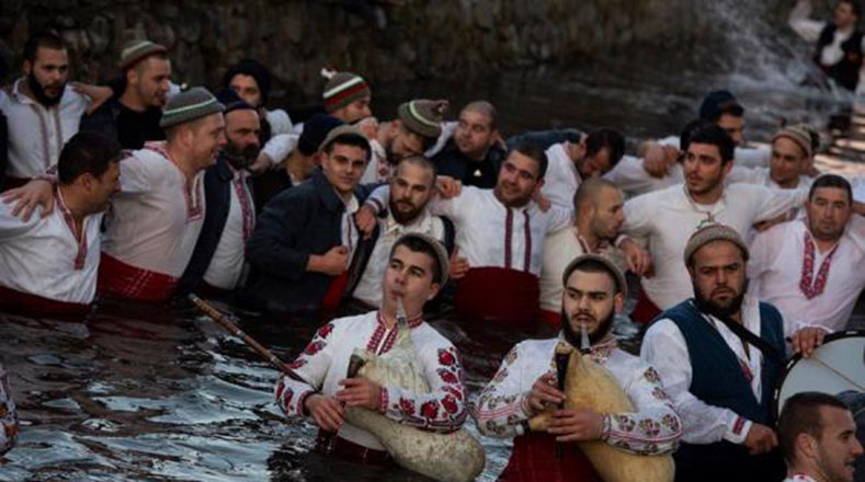 En Kalofer, Bulgaria, la gente realiza el baile nacional "Horo" sosteniendo banderas nacionales en las aguas heladas del río de la región, como parte de la celebración de la Epifanía, una fiesta cristiana que conmemora la llegada de los reyes.