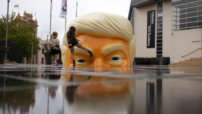 Una niña patea un obra de arte que representa a la cabeza de Trump, en la Galería de Arte de Ballarat, Australia.