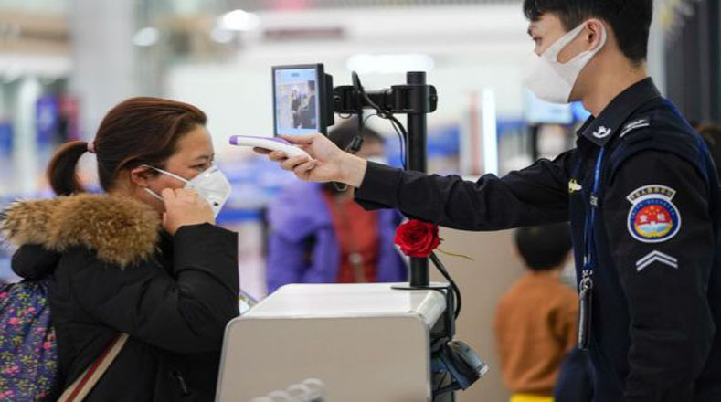 Personal de seguridad del Aeropuerto Jiangbei de Chongqing en China verifica la temperatura corporal de los usuarios.