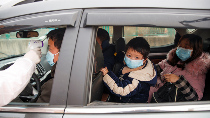 Un trabajador médico verifica la temperatura corporal de un conductor en un puesto de control en China.