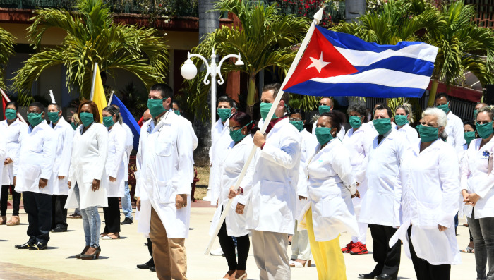 Un médico sostiene una bandera nacional cubana durante una ceremonia de abanderamiento previo a su partida hacia Angola.