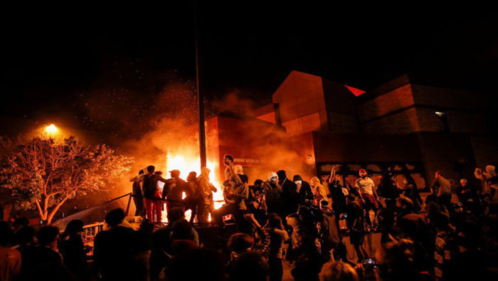 Un grupo de manifestantes rodea un edificio en llamas de la policía de Minnesota.