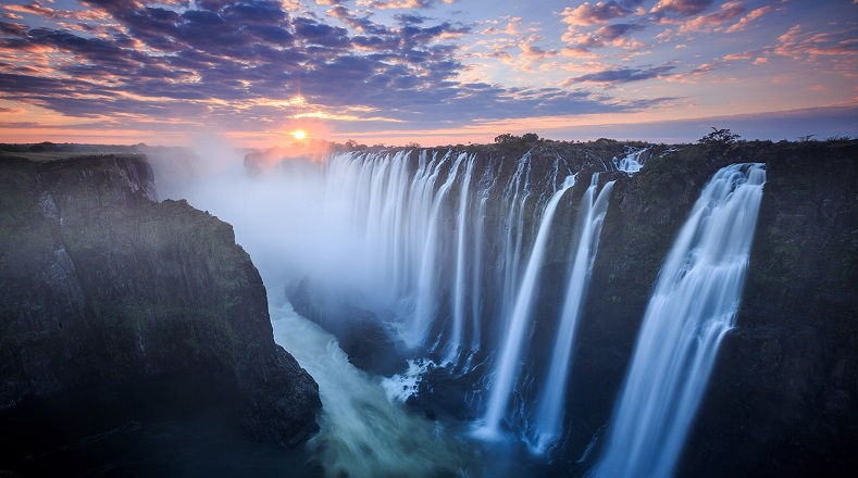 Salto de agua del río Zambeze, ubicado entre Zambia y Zimbabue. El explorador David Livingstone las llamó Cataratas Victoria, pero localmente las llaman Mosi-oa-Tunya, "el humo que truena". Sus atardeceres se pintan de colores.
