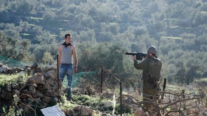 Un jóvenes palestino es amenzado por un soldado israelí durante una protesta semanal en Cisjordania.