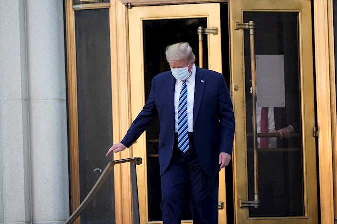 US President Donald J. Trump, wearing a mask, emerges from the front door of Walter Reed National Military Medical Center, in Bethesda, Maryland, USA, 05 October 2020, to board Marine One for a return trip to the White House after receiving treatment for a COVID-19 infection.