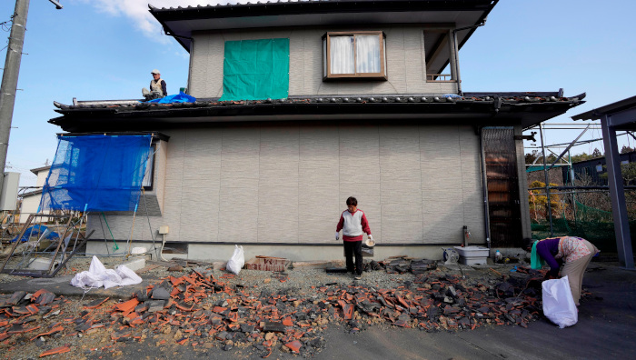 Residentes recogen tejas dañadas tras el terremoto de magnitud 7.1 en Soma, prefectura de Fukushima, Japón.