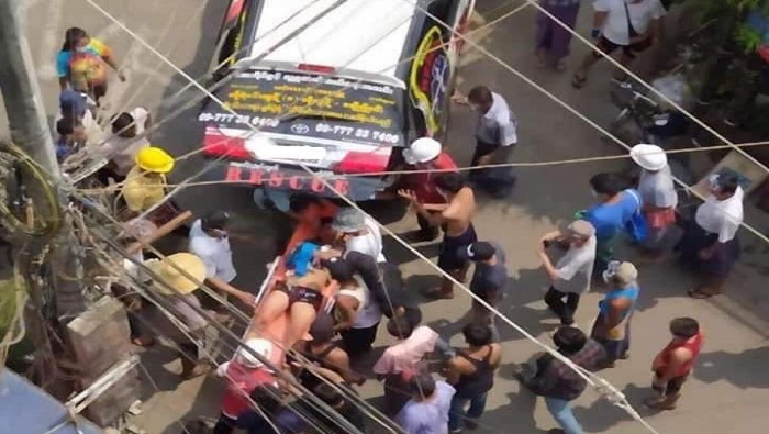 Ciudadanos y miembros de los servicios de emergencia asisten a un hombre herido por disparos de militares en Rangún, ciudad más grande del país.