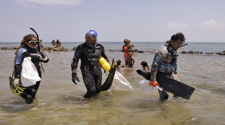 Buzos ingresan al mar en la playa de Buche, en el estado Miranda, Venezuela, para iniciar con la jornada de limpieza.
