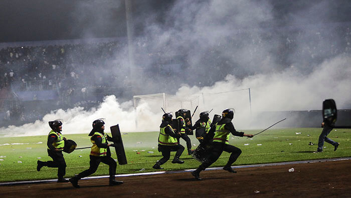 Policías tratan de contralar a la multitud tras el enfrentamiento entre hinchas y jugadores del equipo Arema.