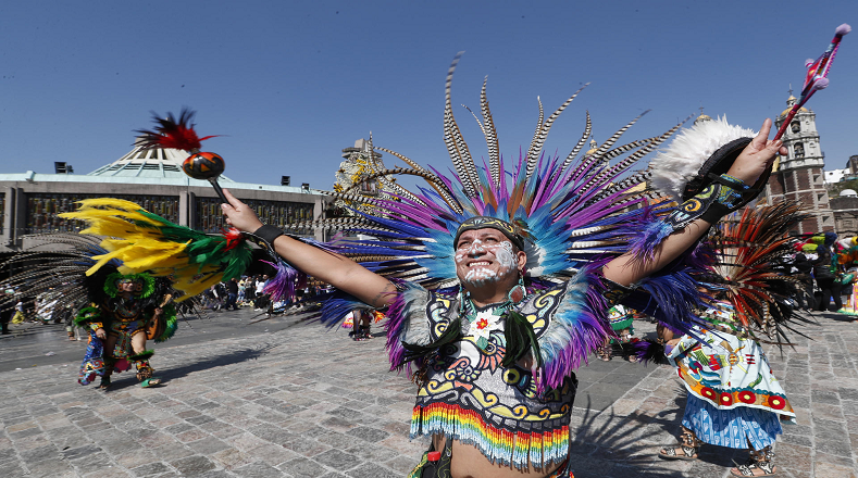 Un mexicano con vestimenta de guerrero azteca danza en el atrio guadalupano para conmemorar el aniversario de la Virgen.