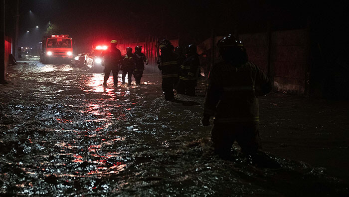 Bomberos chilenos colaboran en la evacuación de una población debido a la crecida del río Maule.
