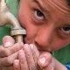 A boy drinks water directly from a tap.